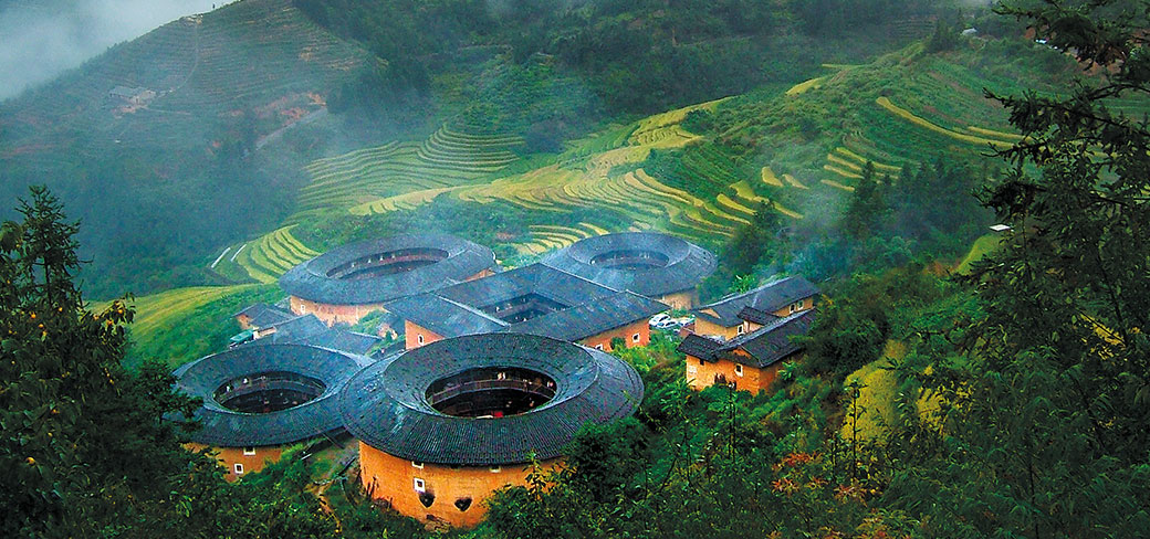 Des bâtiments de terre circulaires et rectangulaires blottis les uns contre les autres et se fondant dans leur environnement naturel. SHEN ZHIJIAN / FOR CHINA DAILY