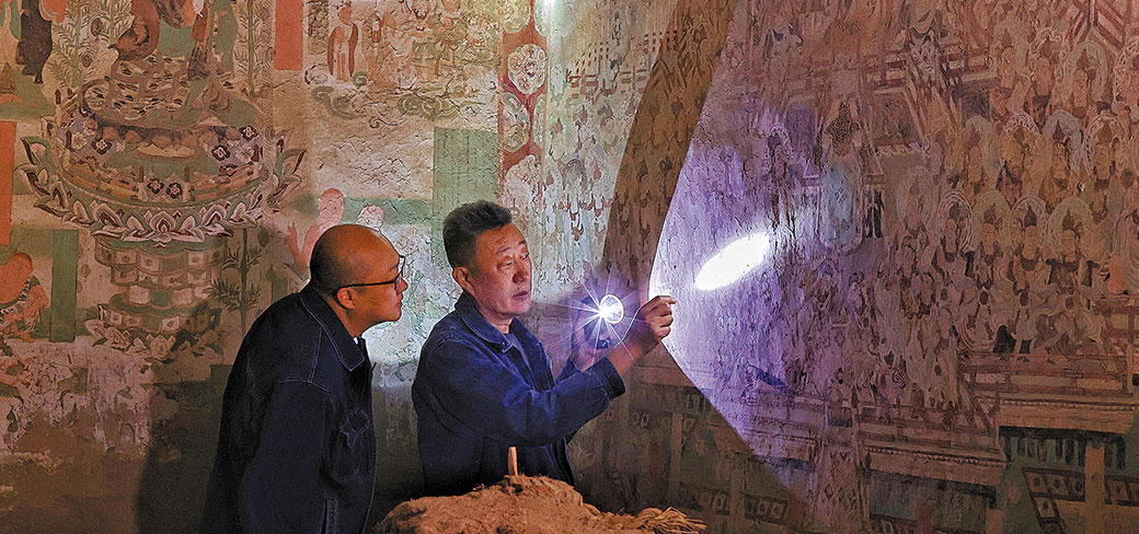 Li Bo (à droite), un restaurateur chevronné de l’Académie de Dunhuang, examinant avec un collègue les peintures murales dans l’une des grottes de Yulin, dans le comté de Guazhou près de Dunhuang, dans la province du Gansu. JIANG DONG / CHINA DAILY