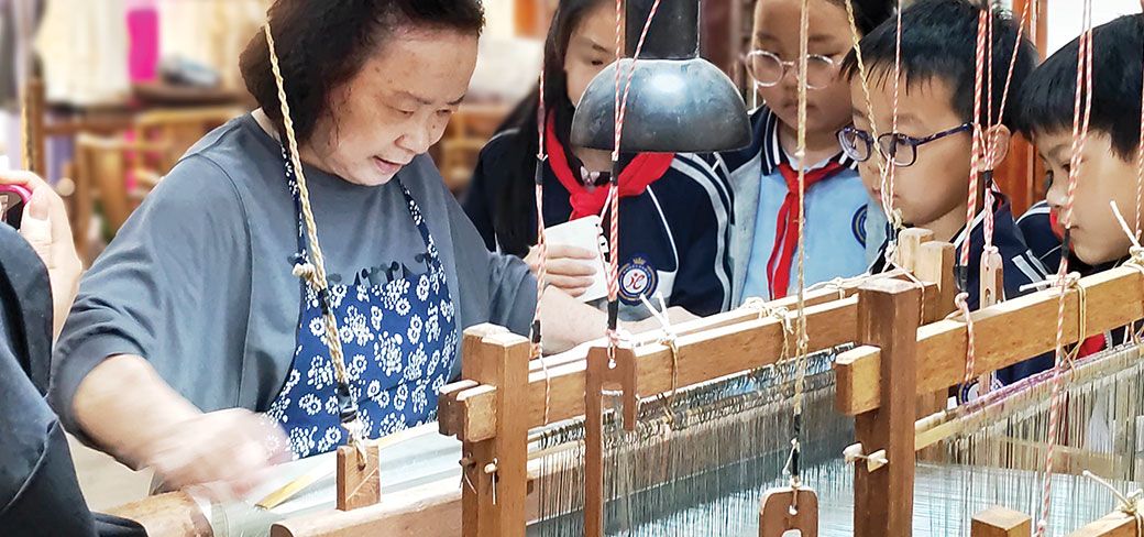 Une héritière de l’artisanat hangluo démontrant devant des élèves cette technique de tissage. PROVIDED TO CHINA DAILY