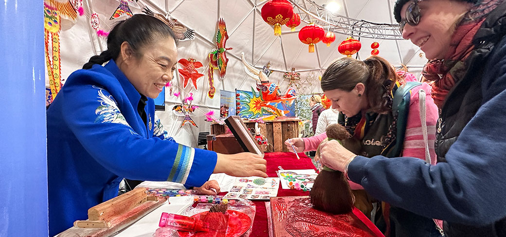 Mme Yang présentant des pièces exposées aux visiteurs du Festival international du cerf-volant de Berck-sur-Mer, fin avril. PROVIDED TO CHINA DAILY