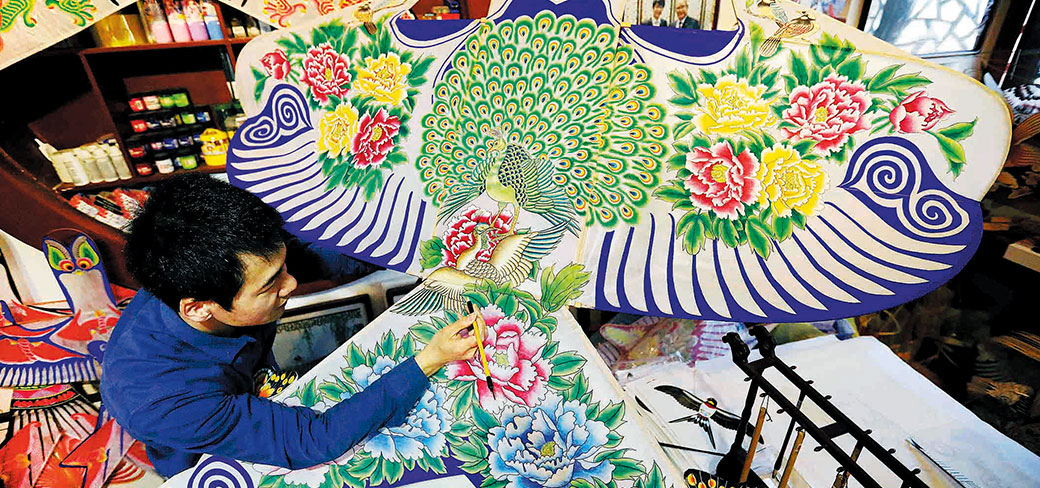 Miao Bogang, un artisan de 43 ans, se consacrant à la peinture d’un cerf-volant en forme d’hirondelle. Il est un héritier représentant des techniques de fabrication de cerfs-volants à Pékin. PROVIDED TO CHINA DAILY