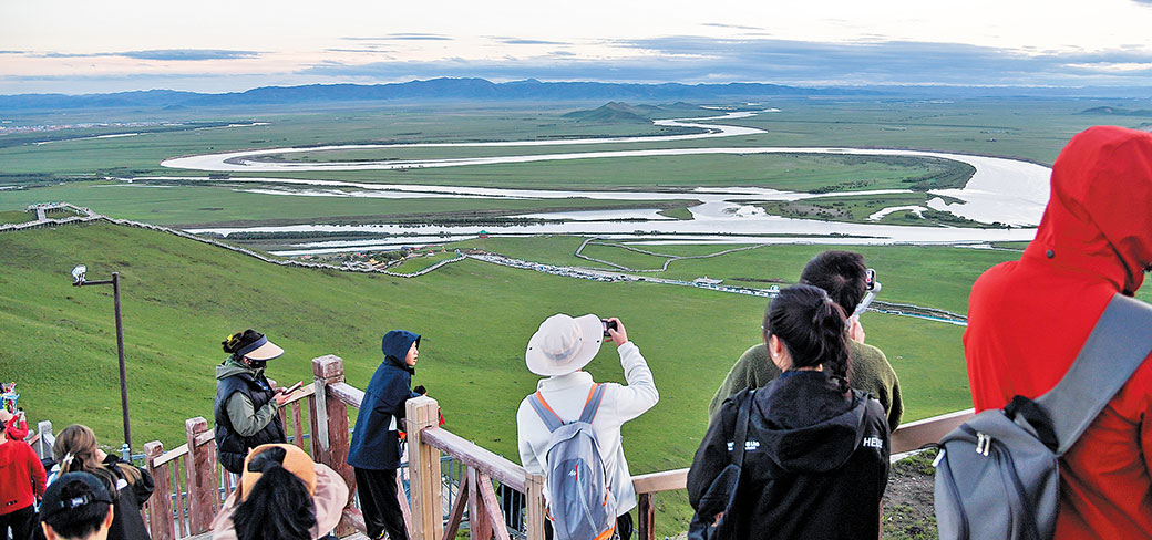 Des touristes photographiant le paysage panoramique du premier coude du fleuve Jaune dans le comté de Zoige de la province du Sichuan, en juin dernier. WANG XI / XINHUA