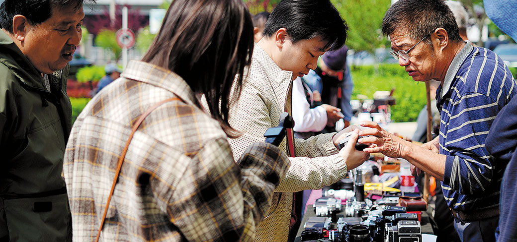 Des passionnés de photographie choisissant du matériel et des accessoires d’appareil photo dans une bourse d’échange à Pékin le 21 avril. SONG JIARU / FOR CHINA DAILY