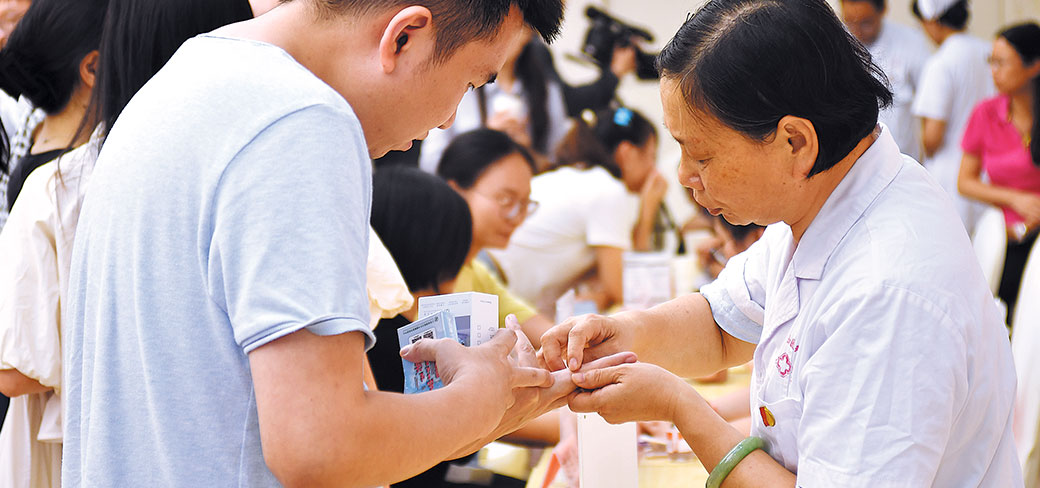 Une employée du service médical donnant des conseils sanitaires à un jeune patient lors d’une manifestation scientifique très courue concernant l’acupuncture thermique à Nanchang, dans la province du Jiangxi, le 8 août dernier. PROVIDED TO CHINA DAILY