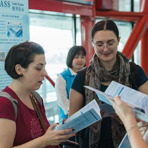 Des voyageurs internationaux lisent des manuels pour Beijing Pass à l'Aéroport international de la Capitale de Beijing, capitale chinoise, le 31 juillet 2024. (Xinhua)