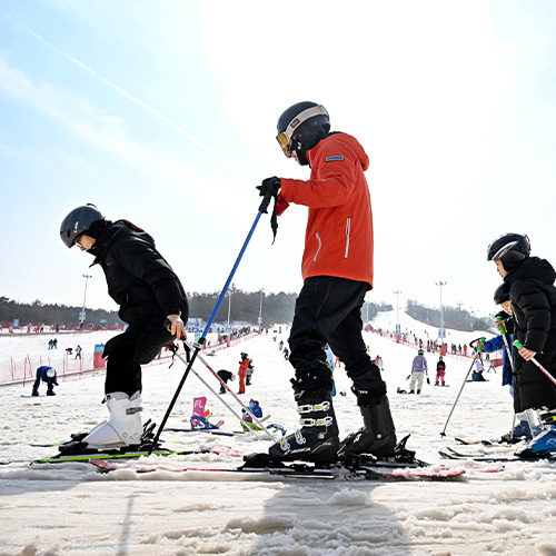 Le 13 février 2026, des visiteurs apprennent à skier à la station de ski dans une station de ski située à Qingdao. (Xinhua/Li Ziheng)